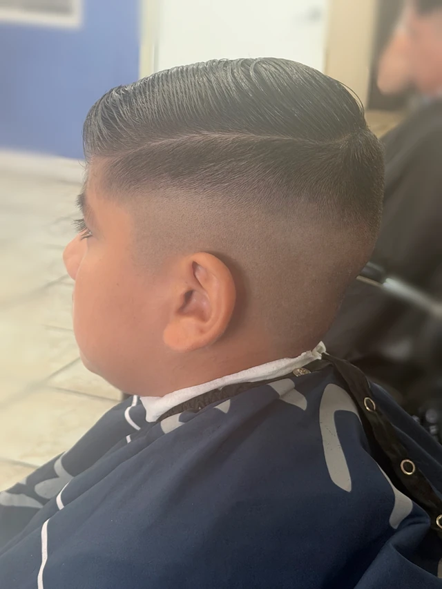 Boy’s side-part haircut with faded sides, viewed in profile.