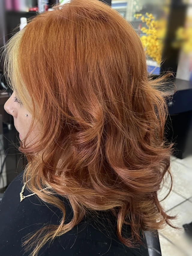 Copper layered curls with a lighter face-framing section, viewed from the side.